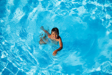 Wall Mural - Happy seven years old boy swimming in the pool