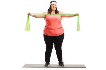 Poster - Overweight woman standing on a mat and exercising with a rubber band