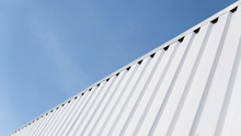 Metal White Sheet For Industrial Building And Construction On Blue Sky Background. Roof Sheet Metal Or Corrugated Roofs Of Factory Building Or Warehouse.