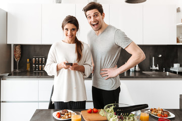 Wall Mural - Portrait of a cheerful young couple cooking together