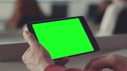 Poster - Man looks at the screen of the tablet with a green screen. Stock. Chroma key on the screen of the tablet in the hands