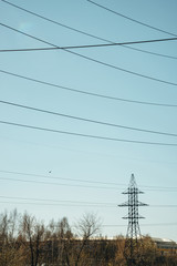 posts with wires of high voltage on background of blue sky in sunlight. background image of many wir