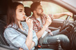 © estradaanton - Couple is sitting in car. Guy is driving and eating candy bar. Girl is looking straight and biting a piece of bar as well. They are safety locked with seatbelt.