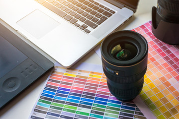 Graphist designer photographer desk with color chart, lens, laptop and digital tablet