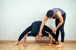© yurakrasil - young and athletic man practices yoga and performs asanas together with an instructor in the gym