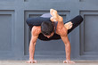 © uv_group - Man doing yoga exercises and practicing handstand balance pose on grey urban background.