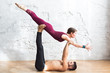 © uv_group - Couple practicing acro yoga poses in studio or gym. Men and woman, pair and acroyoga flexibility class workout on white brick wall background
