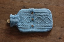 Hand Knitted Hot Water Bottle Cover On Wooden Background. Sud Tirol, Italy