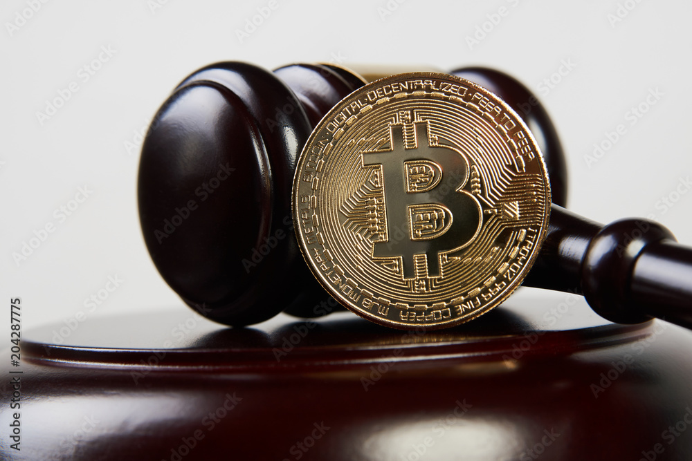 Auction gavel and bitcoin cryptocurrency money on a wooden desk, close-up. Law Gavel and golden bitcoin symbol on white background  with copyspace. Crypto currency law theme