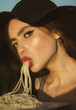 © Volodymyr - Female holding plate of spaghetti in one hand and eating with mouth