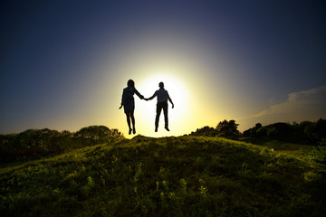 enthusiastically two people jumping on the hill