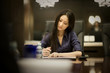 © Erickson Stock - Young adult business woman taking notes in a boardroom.