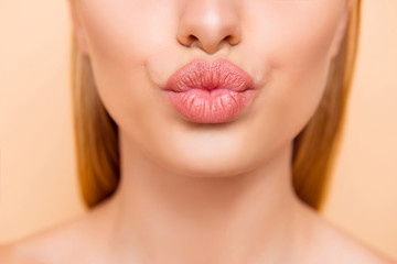 Air kiss for you. Close up cropped shot of femenine gorgeous charming adorable lady with nude natural full big pout lips isolated on beige background, perfection wellness wellbeing concept