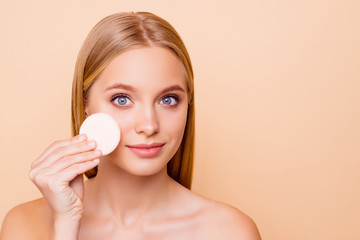 Pretty girl with problem oiled dry skin removing make up with cotton pad from cheek, daily, everyday care concept isolated on beige background with copy space, empty place, advertisement, concept