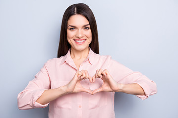 Sticker - Portrait of pretty, charming, sweet, cute, nice, good woman in classic shirt with beaming smile making heart figure love symbol with fingers looking at camera isolated on grey background