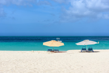  Parasols and sun beds on the shore of an idyllic caribbean beach