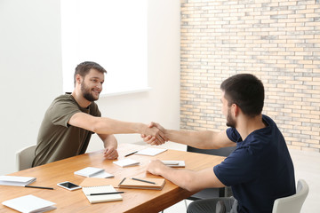 Poster - Two young men shaking hands over table. Unity concept