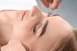 © New Africa - Young woman having professional eyebrow correction procedure in beauty salon