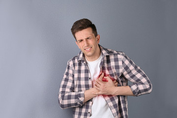 Wall Mural - Young man having heart attack on color background