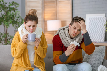 Poster - Couple suffering from cold together on sofa at home