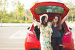© chompoo - Enjoying woman with her girlfriend traveler sitting on hatchback red car. summer vacation, holidays, travel, road trip and people concept .