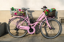 Old Pink Bicycle With Flowers In Front Of A Building