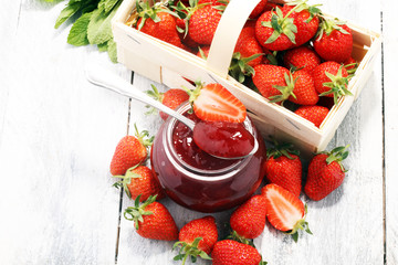 Strawberry jam in a jar and fresah strawberries.