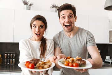 Wall Mural - Portrait of an excited young couple holding dinner plates