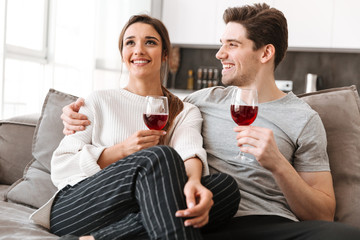 Wall Mural - Portrait of a smiling young couple relaxing on a couch