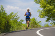 © TheVisualsYouNeed - young attractive sport runner man training in asphalt road running workout a sunny Summer morning surrounded by trees and vegetation