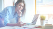 © lenets_tan - Beautiful young business woman sitting at office desk and talking on cell phone. Business woman