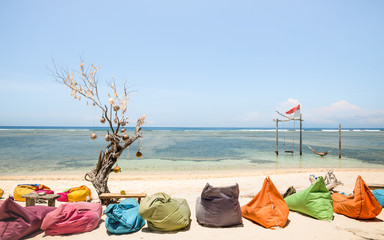 Gili Trawangan beach on a sunny day with multicolored sofas at chilling lounge - Travel and vacation concept with beautiful destinations worldwide - Bali and Lombok environments in Indonesia islands