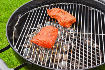 Raw marinated beef steak on the grill.