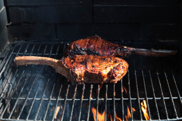 Tomahawk rib beef steak on hot black grill with flames