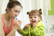 © Oksana Kuzmina - smiling mother and kid daughter brushing teeth in bathroom