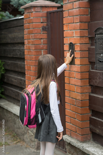 Fotografie, Obraz Little girl in school uniform ringing door bell