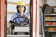 © Mint Images - Female employee using forklift