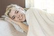 © 2Design - A beautiful happy content woman lying in bed smiling at camera.