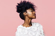 Profile portrait of a beautiful young woman with curly black hair, isolated on pink background