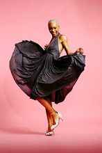 Portrait Of A Beautiful Young Woman With Very Short Platinum Hair In Pleated Dress Dancing, Isolated On Pink Studio Background