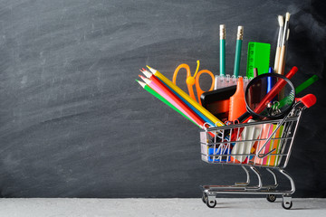 Wall Mural - Shopping cart with stationery near blackboard