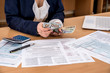 © RomanR - woman counts money by filling in tax forms