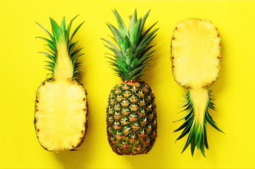 Wall Mural - half slice of fresh pineapple and whole fruit on yellow background. top view. copy space. bright pin