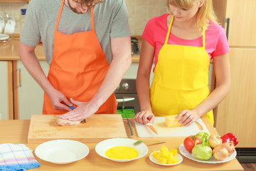 Man cutting meat on board. Couple in kitchen