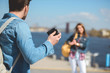 © LIGHTFIELD STUDIOS - rear view of male traveler with backpack shooting girlfriend on camera