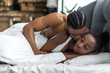 © LIGHTFIELD STUDIOS - african american boyfriend kissing sleeping girlfriend in bedroom