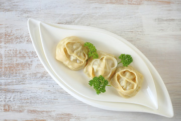 Wall Mural - dumpling. Homemade manti dumplings in a white dish  with parsley   on a light  background. Manti . Traditional meat dish.