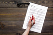 © 9dreamstudio - Take the exam, write the exam. Hand holding pen near exam paper on dark wooden background top view copy space