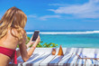 © astrosystem - Girl using cellphone in the restaurant on a exotic tropical beach.