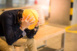 © zephyr_p - Young Asian engineer or architect man feeling tried and worried while sitting on bench holding his personal yellow protective safety helmet. depression from hard work concept